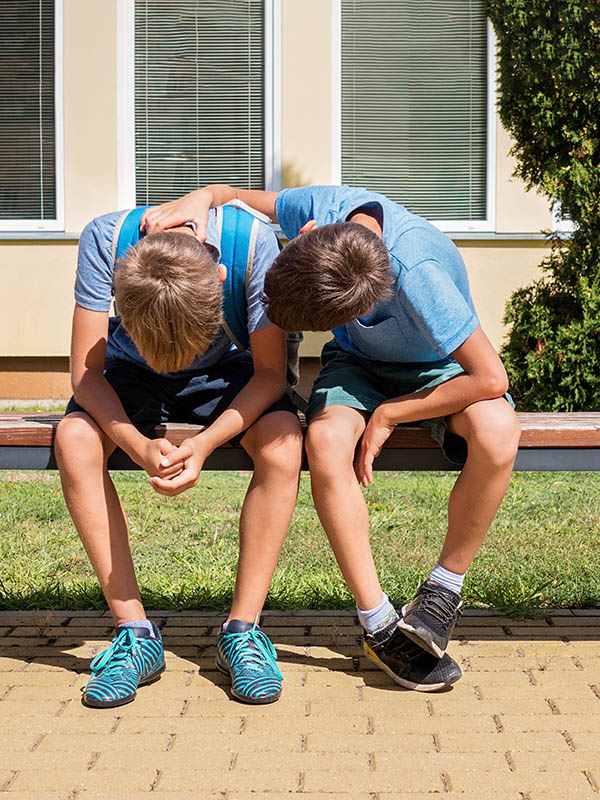 Kid comforting consoling upset sad boy in school yard