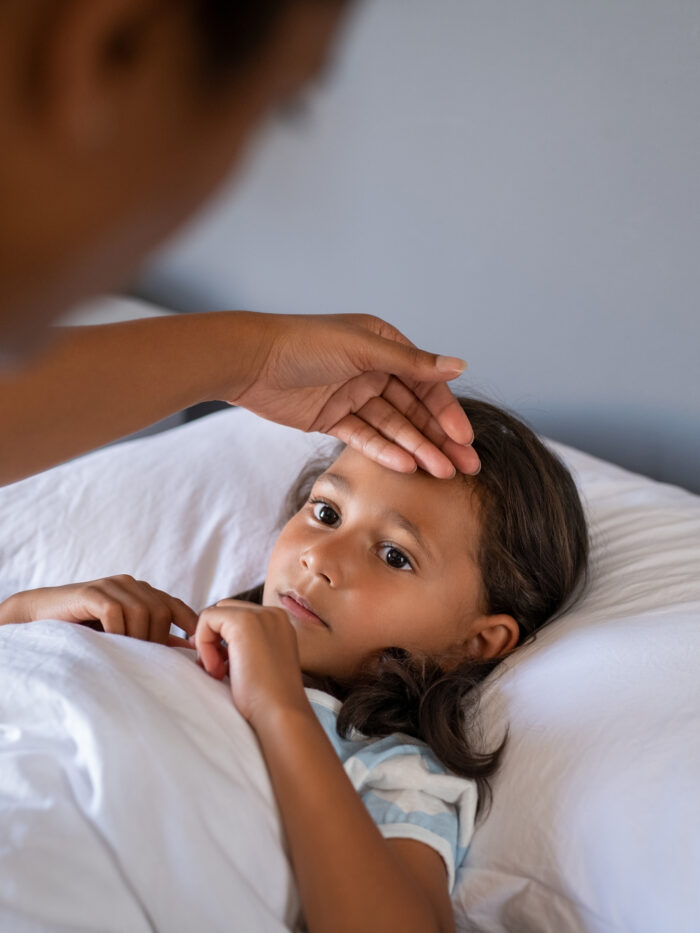 Madre revisando la temperature de su hija con fiebre
